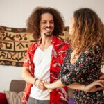 Una pareja sonriente bailando bachata en casa